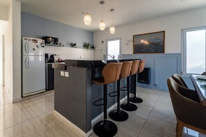 Eine moderne Küche mit einer zentralen Kochinsel, Barhocker und einem Essbereich mit Tisch und Stühlen.