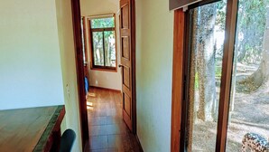 Un pasillo con suelo de madera, una zona de bar con taburetes y grandes ventanales que ofrecen vistas al exterior.