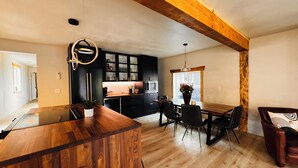 A modern kitchen with dark cabinets, a wooden island, and a dining area with a table and chairs. - Luxury Living Near Downtown Moscow & U of I Campus (Moscow)