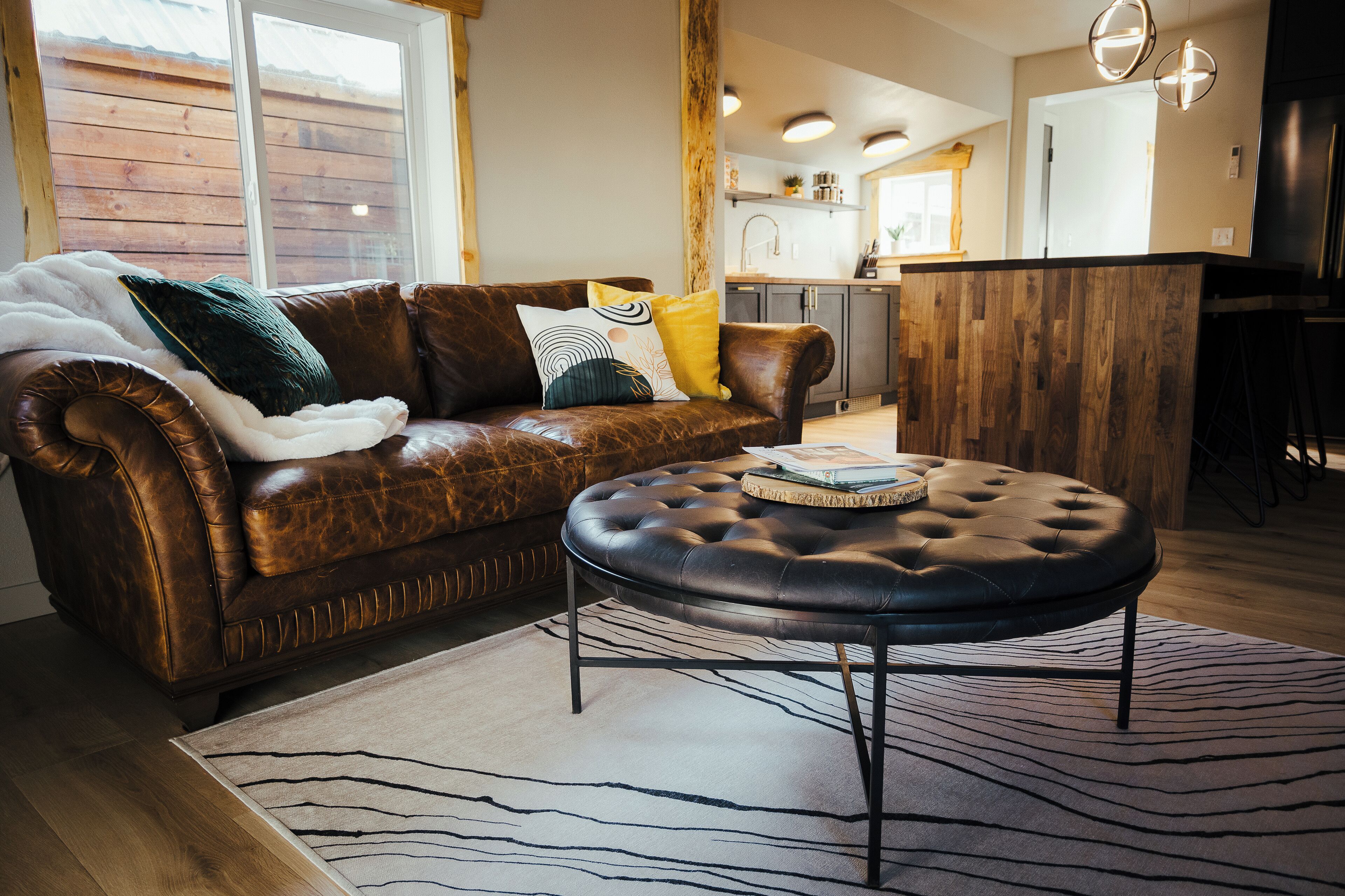 Ein Wohnzimmer mit einem braunen Ledersofa, einem schwarzen Ottomanen und einem Zebra-Teppich.