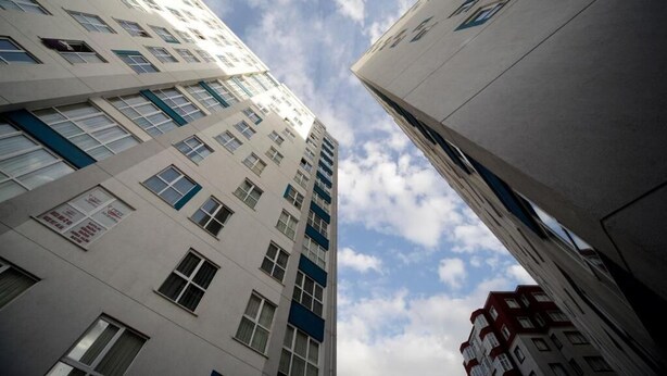 Ein Hochhaus mit zahlreichen Stockwerken, großen Fenstern und wolkenüberspannter Himmel.