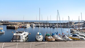 Een jachthaven met diverse boten afgemeerd, een heldere lucht en een rustige zee.