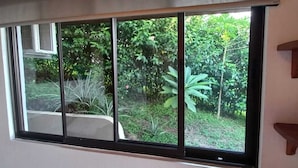 A room with a large window offering a view of a lush garden.
