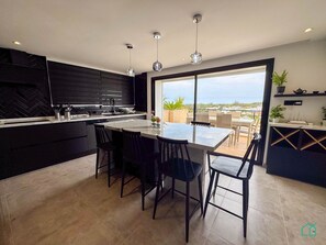 Cozinha moderna com ilha grande, armários pretos e vista para a cidade.