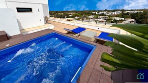 A rooftop pool with blue water, surrounded by lounge chairs and a wooden deck. - The Penthouse Gammarth (La Marsa)