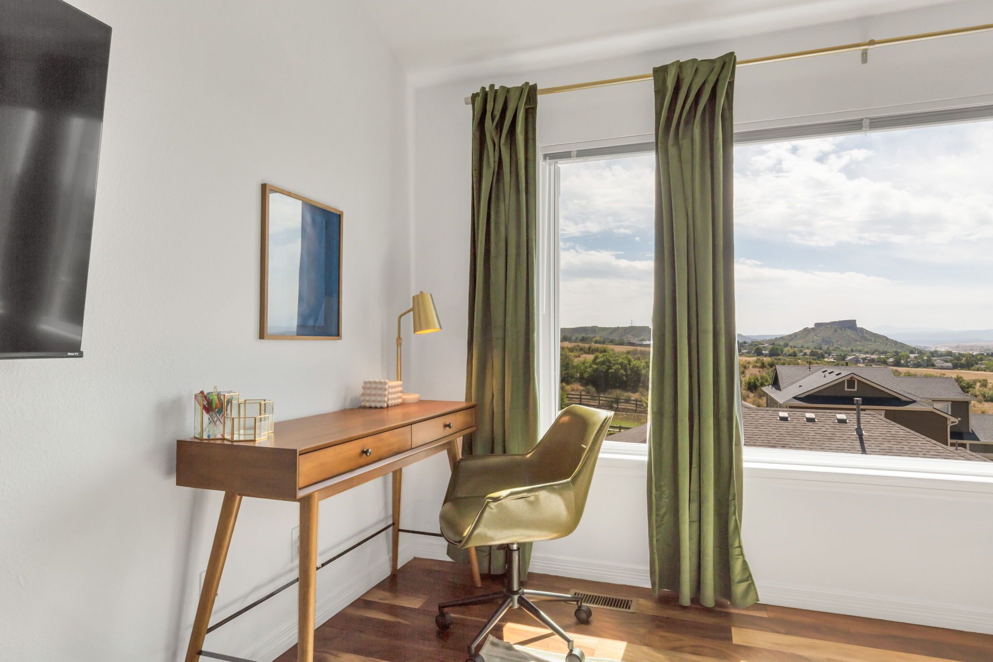 Une pièce comprenant un bureau, une chaise et une fenêtre avec des rideaux.