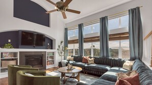 Una sala moderna con chimenea, un sofá modular y un ventilador de techo.