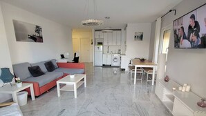 A modern living room with a grey sofa, a coffee table, and a dining area with a wooden table and chairs.