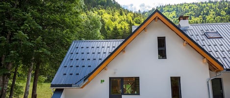 Ein modernes Haus mit schrägem Dach, Solaranlage und weißer Fassade.