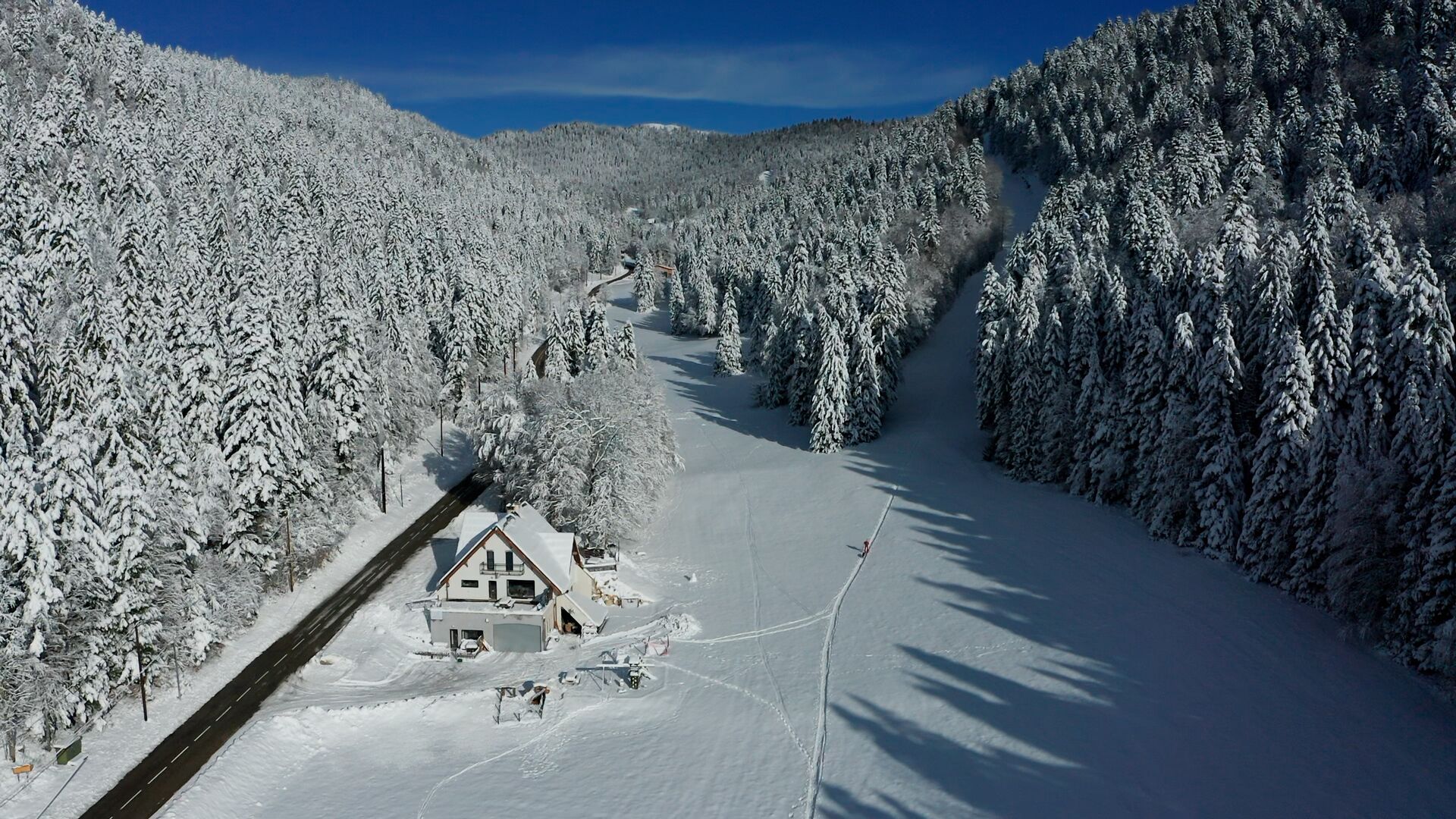 Paisaje nevado con una casa y una pista de esquí.
