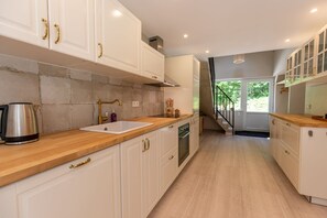 Una cucina moderna con mobili bianchi, un piano di lavoro in legno e un bollitore in acciaio inossidabile.