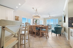 A dining area with a chandelier, wicker chairs, a table, and a view through the windows.