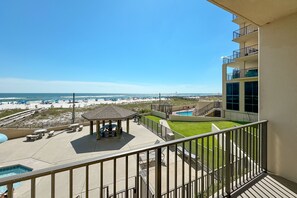 Un balcón con vistas a una playa, una piscina y un pabellón.