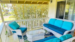A covered porch with wicker furniture and a glass table. - House of Aloha Retreat (Pahoa)