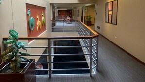 Un moderno vestíbulo de hotel con una escalera central, una zona de estar y una planta grande.