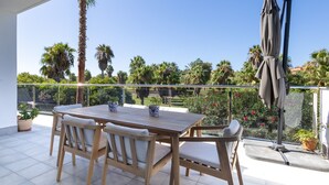A wooden table with chairs on a balcony with a view of palm trees and a garden. - Ref. 503105 (Motril)