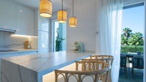 A modern kitchen with a marble island, wicker chairs, and pendant lights. - Ref. 503105 (Motril)