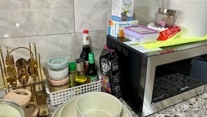 Un piano di lavoro in cucina con diversi oggetti, tra cui un forno a microonde, una macchina per il caffè, una bottiglia di vino Manzanilla, una confezione di caffè Filtrina e un vassoio con una torta.