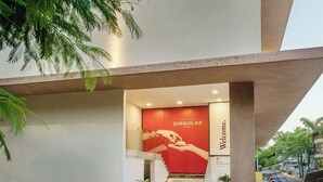 Entrada de un hotel con un gran letrero que dice "SINGULAR HOTEL" y un cartel de bienvenida debajo.