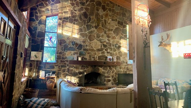 Un interior acogedor con chimenea de piedra, vigas de madera y una zona de estar cómoda.