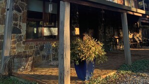 Un edificio de piedra de dos pisos con revestimiento de madera y una planta grande en maceta al frente.