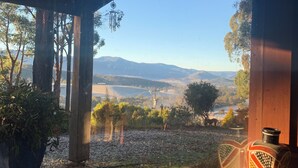 Una estructura de madera con vistas a un paisaje, incluyendo árboles y colinas distantes.