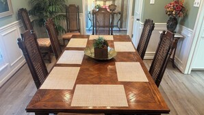 A wooden dining table with woven placemats, surrounded by ornate chairs. - Charming 3-bedroom home in quiet Bryan neighborhood in the heart of AggieLand! (Bryan)