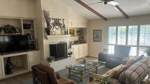 A living room with a fireplace, a television, a sofa, and a chair. - Charming 3-bedroom home in quiet Bryan neighborhood in the heart of AggieLand! (Bryan)