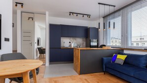 Una cocina moderna con armarios oscuros, una mesa de comedor de madera y un sofá azul con un cojín a rayas.