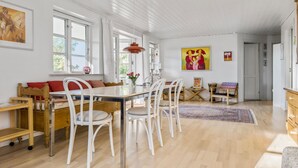 Un grand espace à manger avec une table et des chaises en bois, un canapé et une fenêtre avec des rideaux.