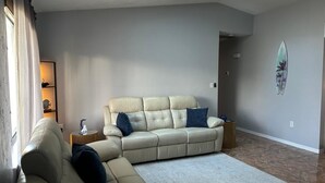 A living room with a beige sectional sofa, a small side table, a decorative wall piece, and a skylight. - Blue Beach Pool House-Port Orange/Daytona (Port Orange)