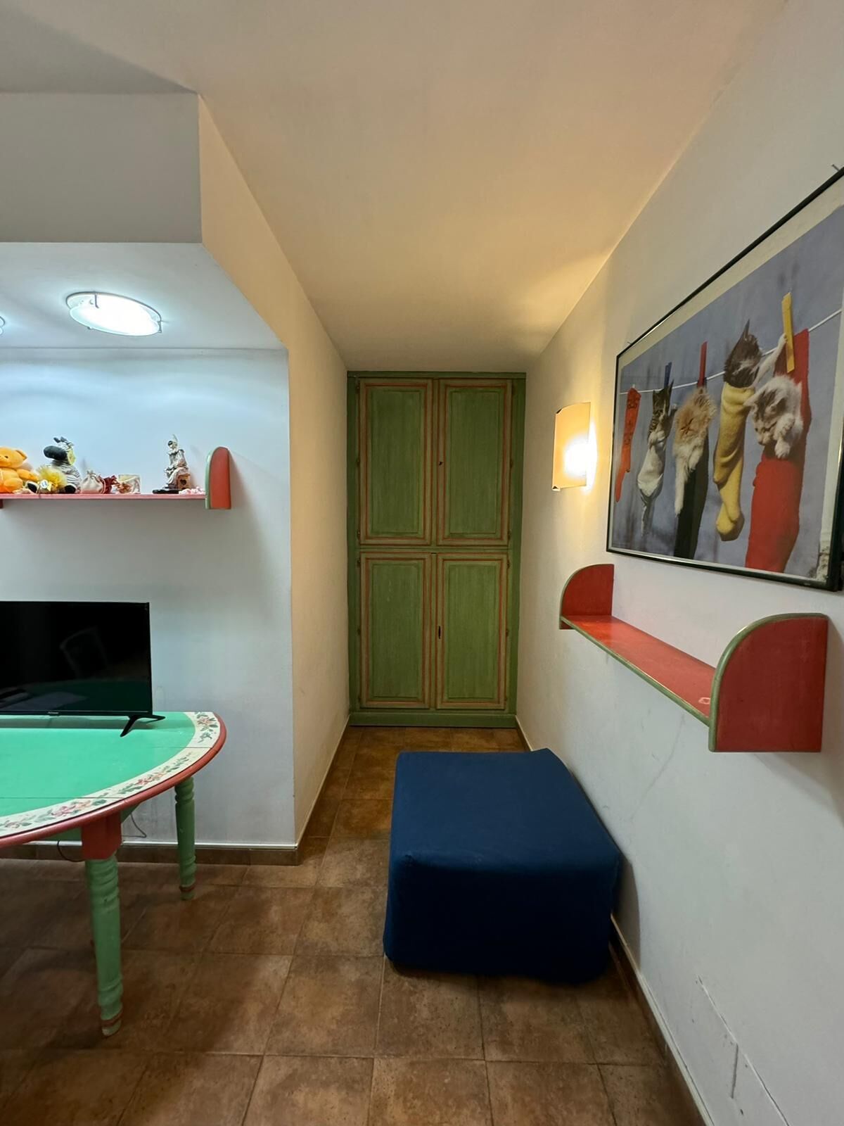A room with a pool table, a green cabinet, a blue bench, and a wall-mounted shelf with a painting.