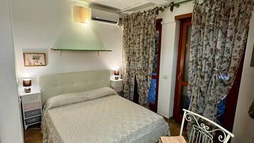 A bedroom with a bed, a nightstand, a chair, and a table with towels.