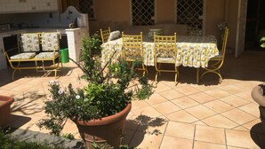 A patio with a dining table, yellow chairs, and a potted plant. -  L'affittacamere nel parco "Appia Antica" (Rome)