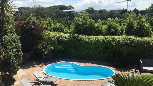 A swimming pool surrounded by lounge chairs and a hedge. -  L'affittacamere nel parco "Appia Antica" (Rome)