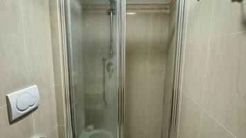Un baño con ducha envuelta en vidrio, un inodoro y un perchero para toallas.