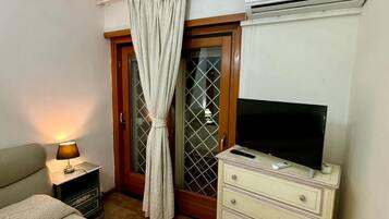 Een slaapkamer met een bed, een dressoir, een televisie en een airconditioning.