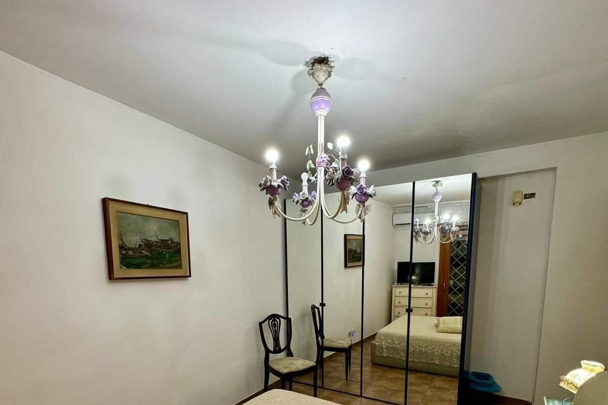 Quarto com uma cama grande, um candelabro, uma cadeira, um espelho e um quadro na parede.