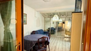 A dining area with a table and chairs, a wooden cabinet, and a glass door. -  L'affittacamere nel parco "Appia Antica" (Rome)