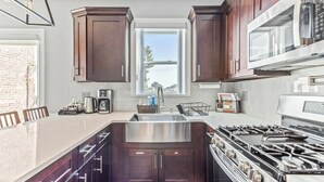 Una cocina moderna con armarios de madera oscura, un lavamanos de acero inoxidable y una estufa a gas.