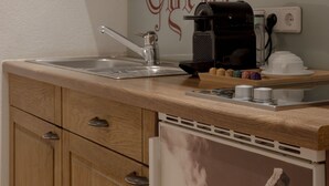 A kitchen with wooden cabinets, a coffee maker, and a wall-mounted microwave. - Sportalm Seefeld - Apartment with breakfast included (Seefeld in Tirol)