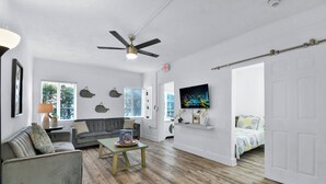 A spacious living room with a grey sofa, a coffee table, and a ceiling fan.