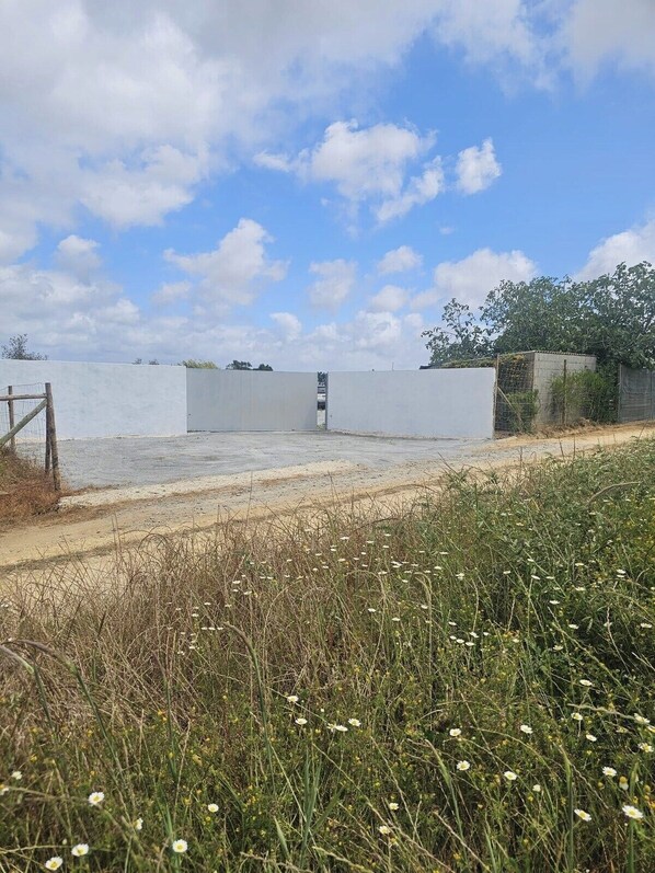 A fenced outdoor area with a concrete path leading to a gate.