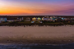 A beachfront property with multiple houses, a sandy beach, and a view of the ocean.