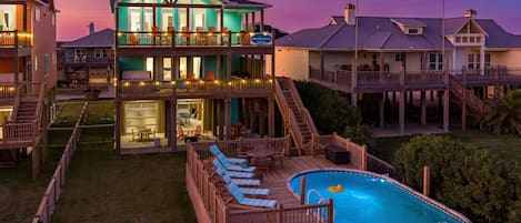 A two-story house with a pool, outdoor seating, and a deck.