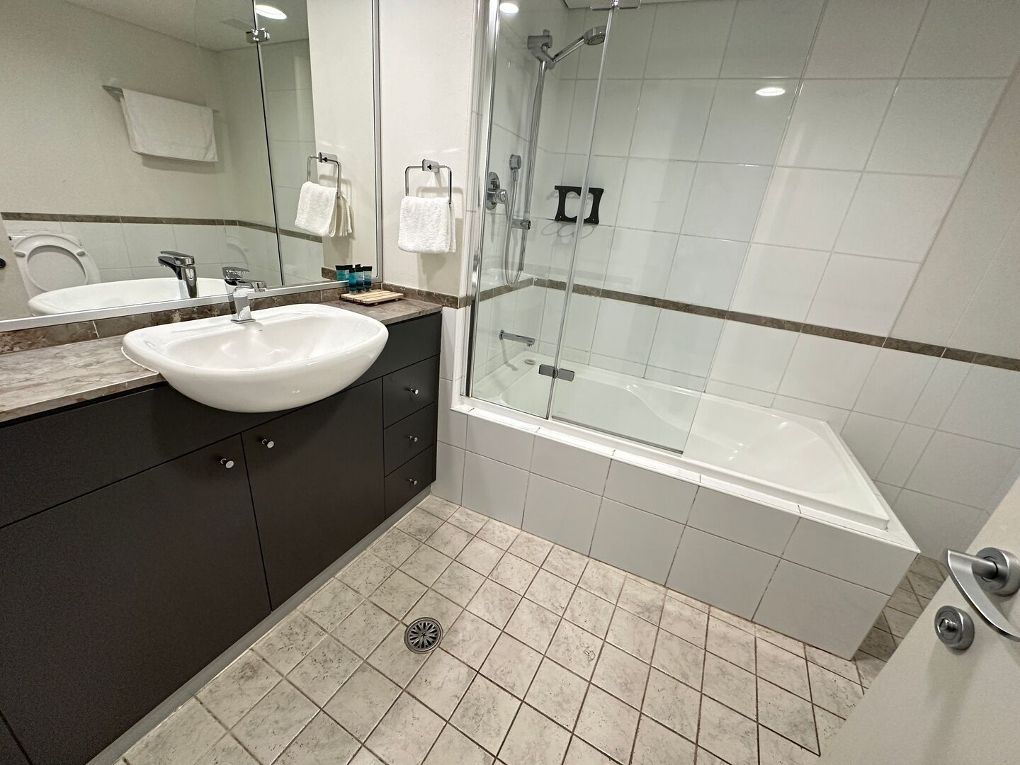A modern bathroom with a large sink, mirror, and shower area.