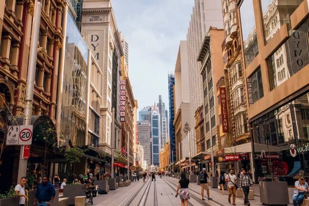 Una calle flanqueada por edificios históricos, incluyendo un llamativo letrero de 'DYM'.