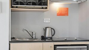 Una cocina moderna con microondas integrado, hervidor y lavavajillas.