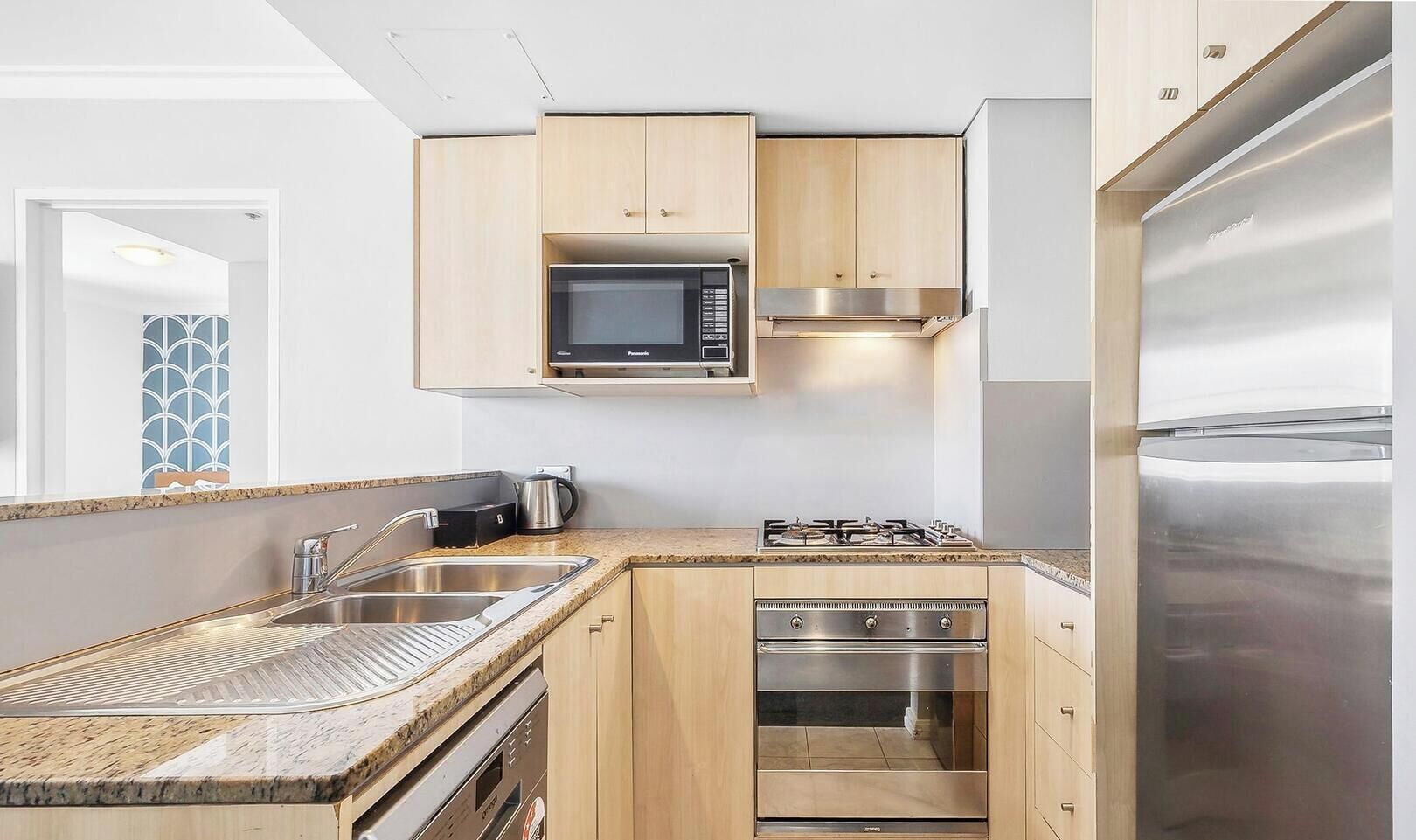 Una cocina moderna con microondas integrado, estufa, horno y refrigerador de acero inoxidable.