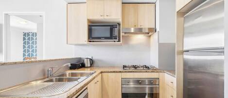 Una cocina moderna con microondas integrado, estufa, horno y refrigerador de acero inoxidable.